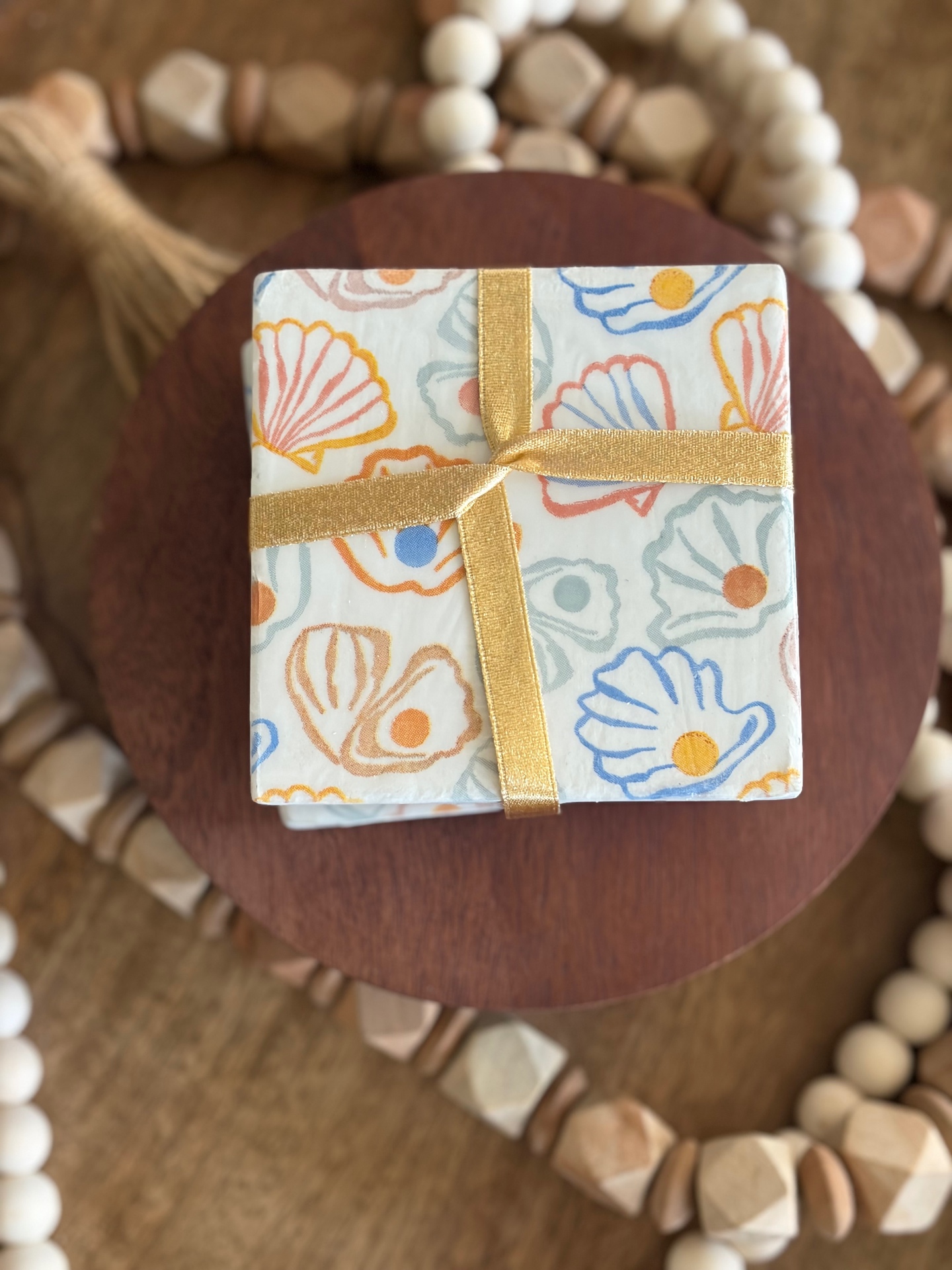 Stack of pastel shell coasters tied with a gold ribbon, ready for gifting.