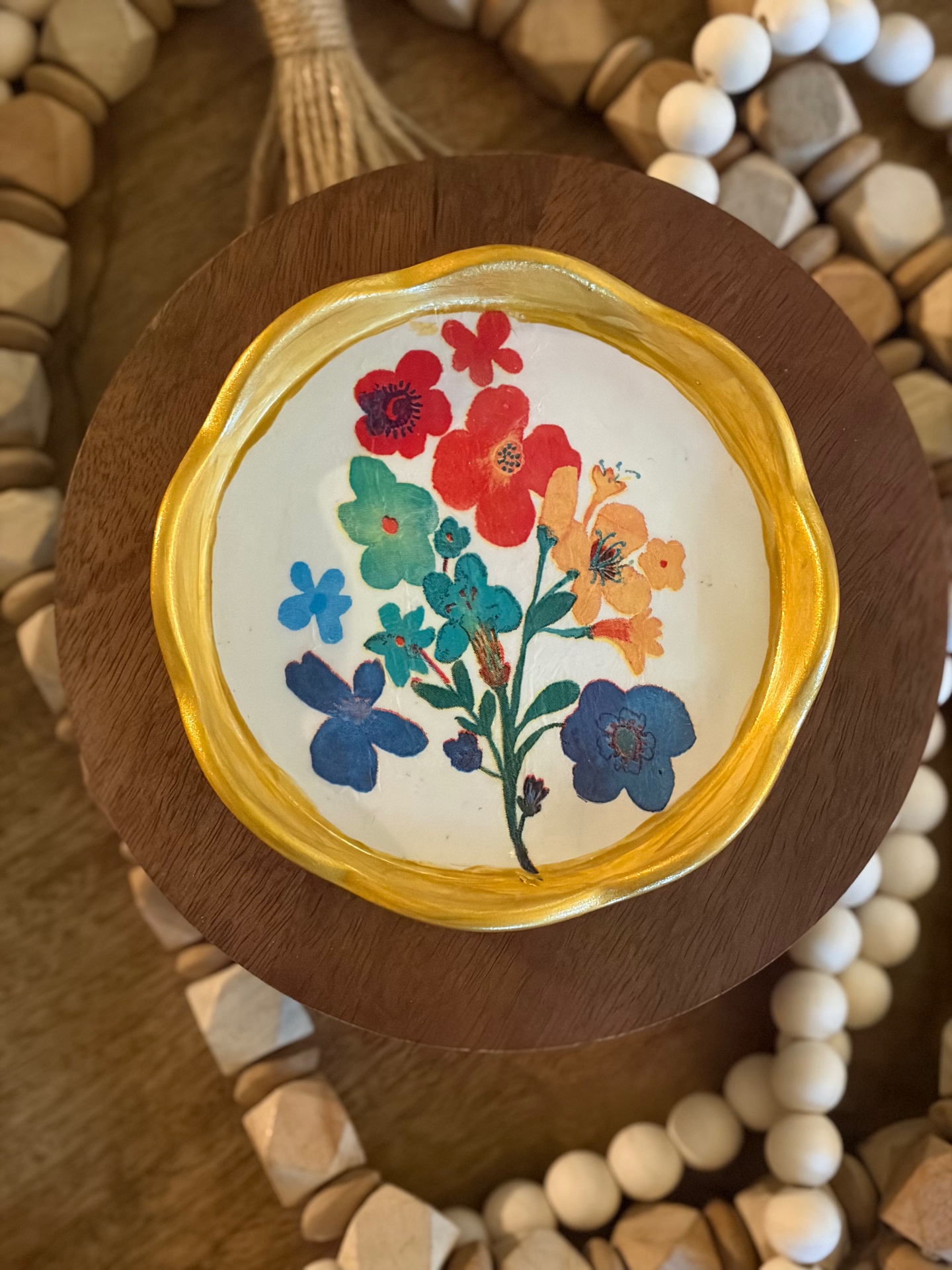 Round white dish with a gold-painted rim and a colorful wildflower bouquet in the center.