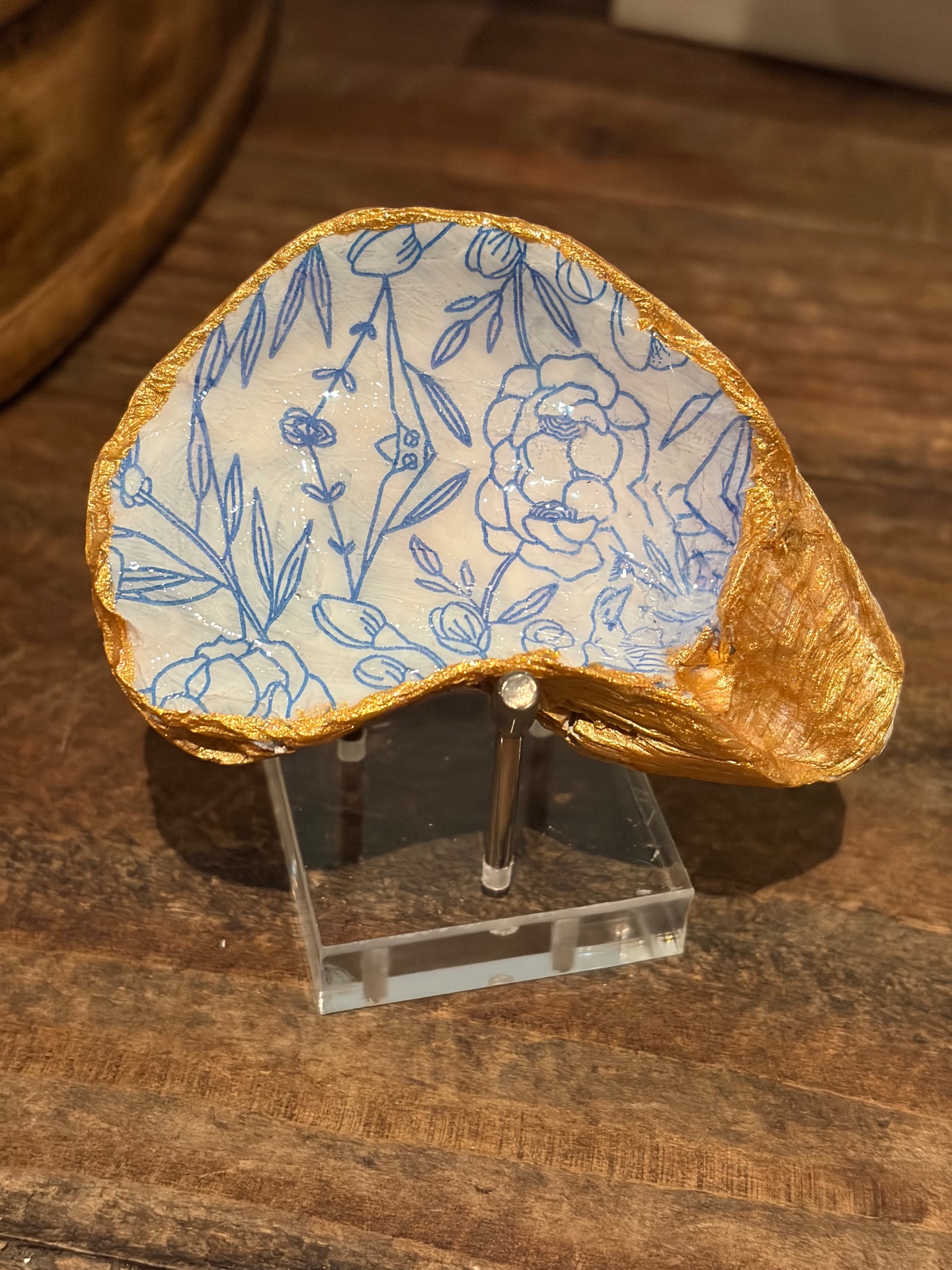 Shell-motif dish displayed upright on a small wooden stand.